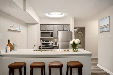 A kitchen with a white counter and brown stools.
