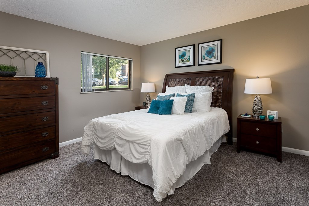 A bedroom with a large bed, a dresser, and two nightstands.