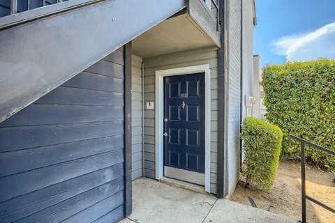 A blue house with a black door and a small window above it.