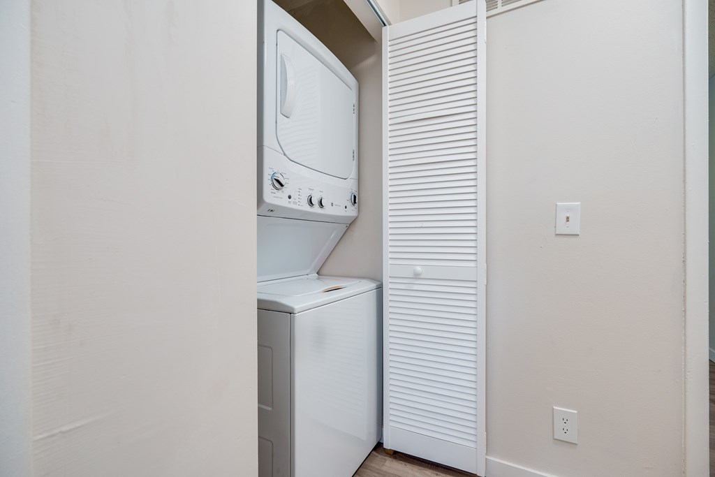 A white dishwasher is in a narrow space between a wall and a microwave.