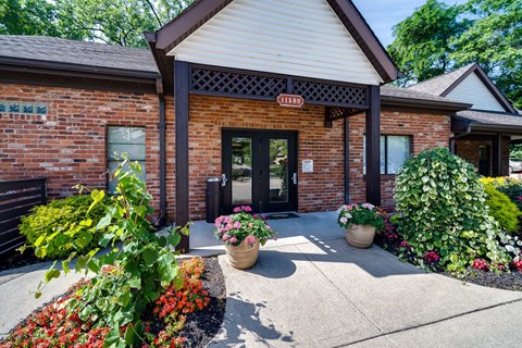 A building with a red brick facade and a sign that reads "TESDA" is surrounded by a variety of potted plants and flowers.