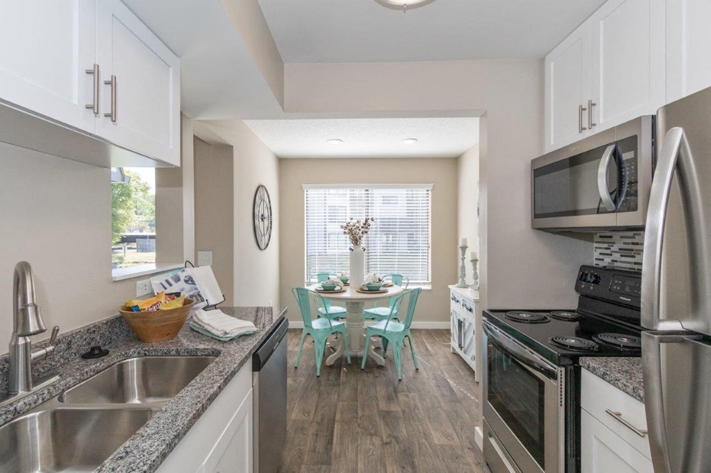 a kitchen with stainless steel appliances, modern white cabinets, and granite countertops