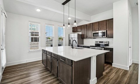 A modern kitchen with dark wood floors and white countertops.