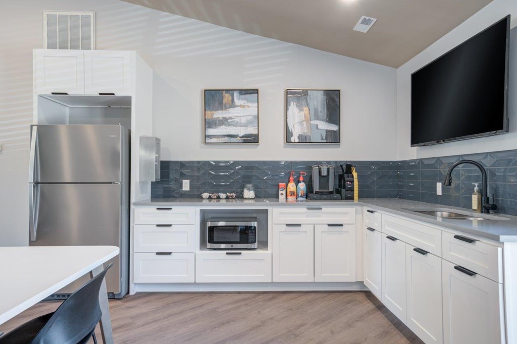 A modern kitchen with white cabinets and a stainless steel refrigerator.