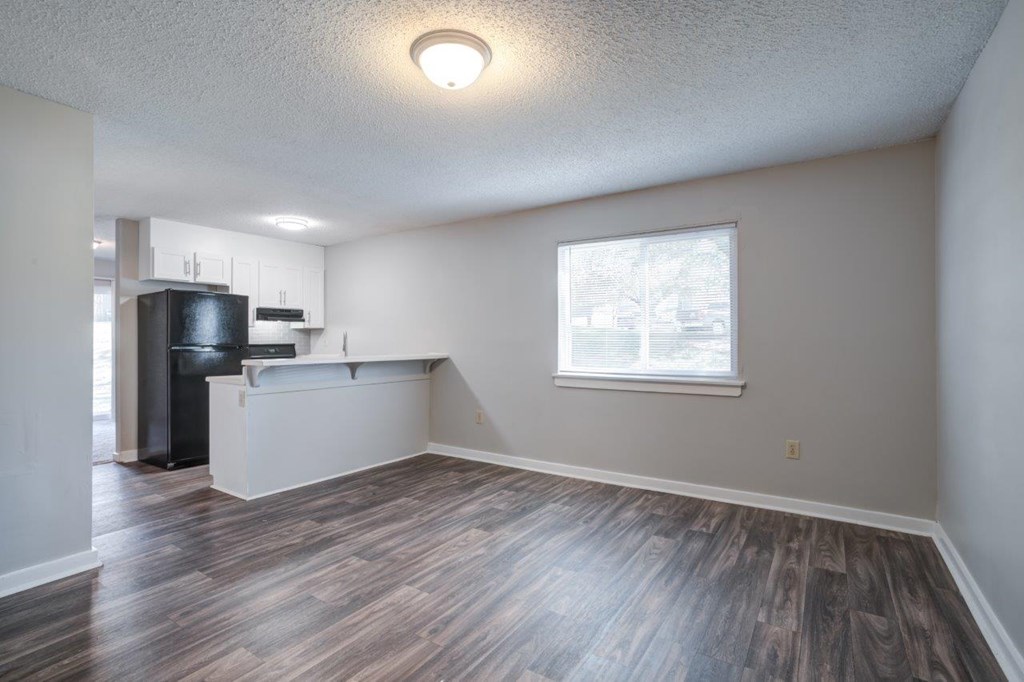 A kitchen area with a black fridge and a window.