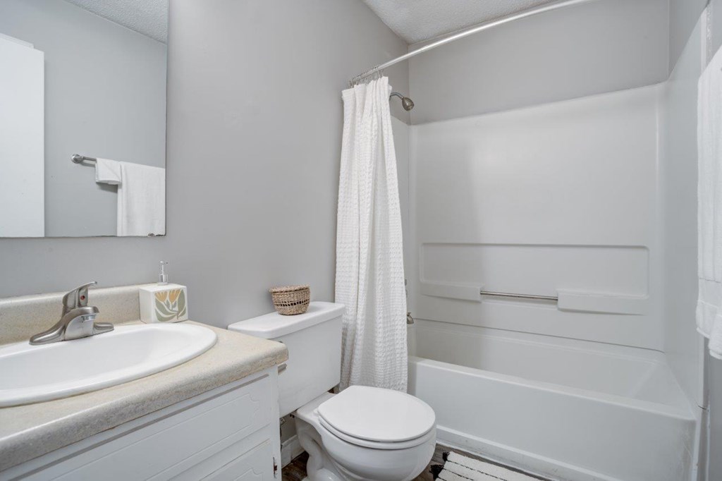 A white bathroom with a toilet, sink, and bathtub.