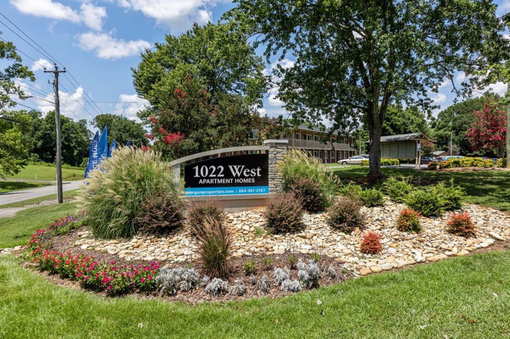 a round rock garden with plants and a sign