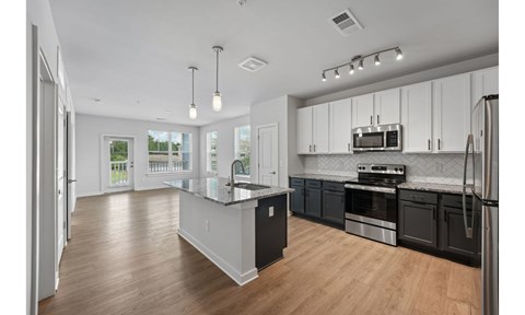 A modern kitchen with a black countertop and stainless steel appliances.