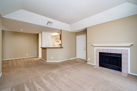 A living room with a fireplace and carpeted floor.