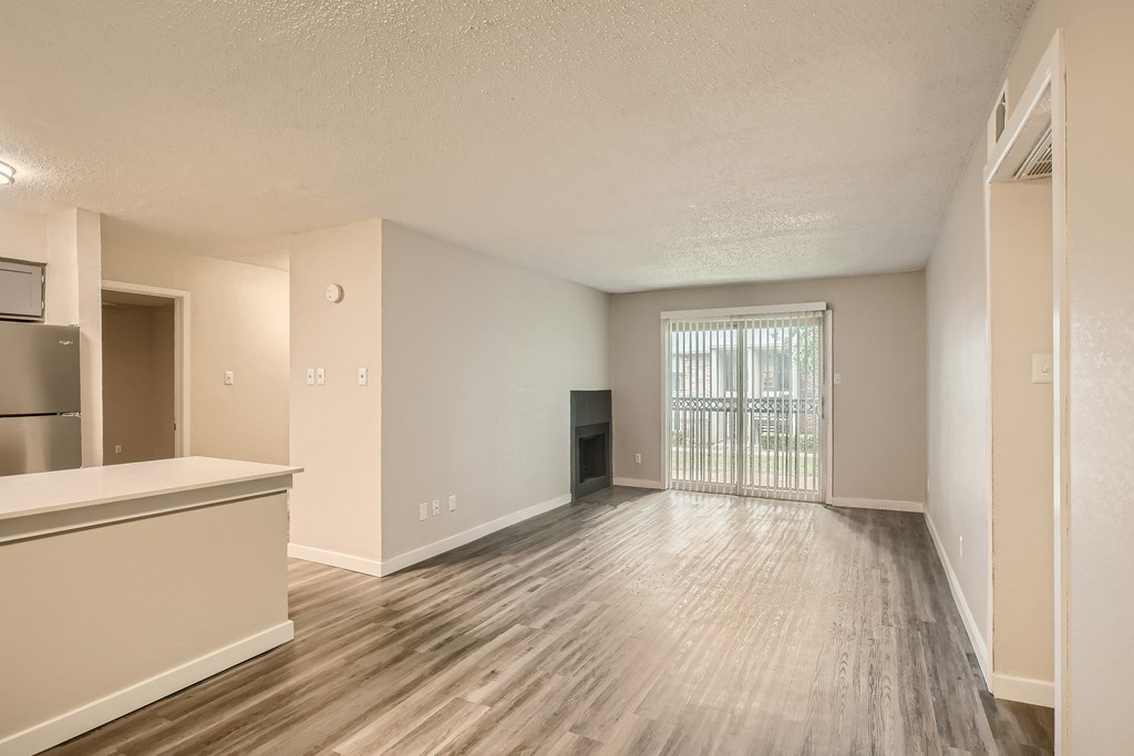 A spacious room with wooden flooring and white walls.