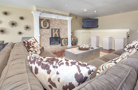 A living room with a large couch and a cowhide pillow.