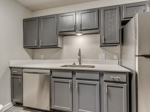 A kitchen with a white counter top and grey cabinets.