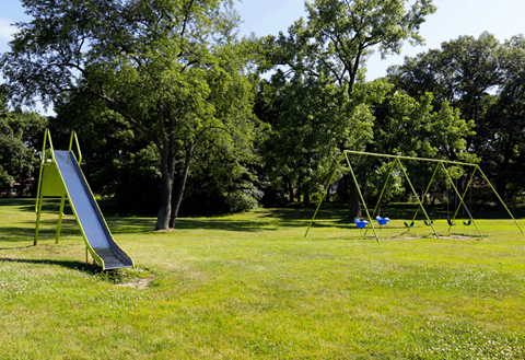 A playground with a green slide and a yellow swing set.