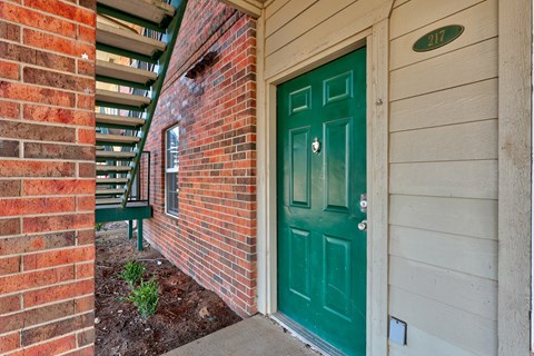 A green door is on the right side of a brick wall.