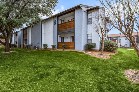 A modern apartment building with a green lawn in front.