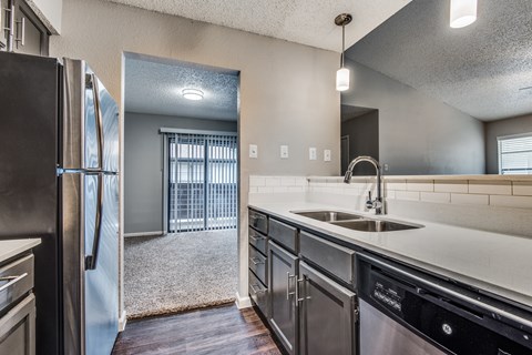 A kitchen with a black refrigerator and stainless steel appliances.