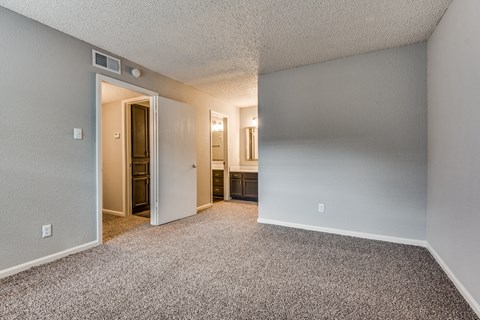 A room with a carpeted floor and a doorway leading to another room.