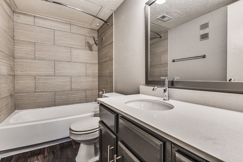 A bathroom with a white tub, sink, and toilet.