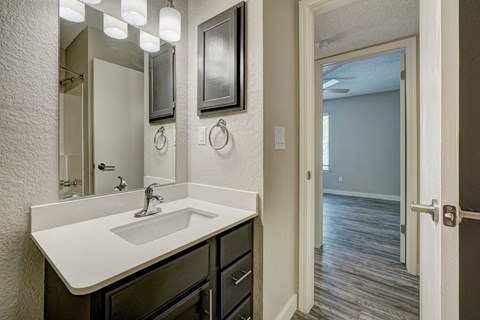 A bathroom with a sink, mirror, and lighting fixtures.