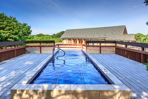 A wooden deck with a pool and a building in the background.