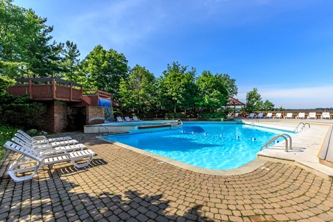 A large outdoor swimming pool surrounded by sun loungers and trees.