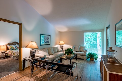 A living room with a couch, chairs, and a table with a lamp on it.