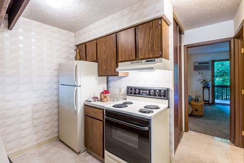 A kitchen with a white refrigerator, a white stove, and wooden cabinets.
