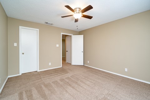 A room with a ceiling fan and carpeted floor.