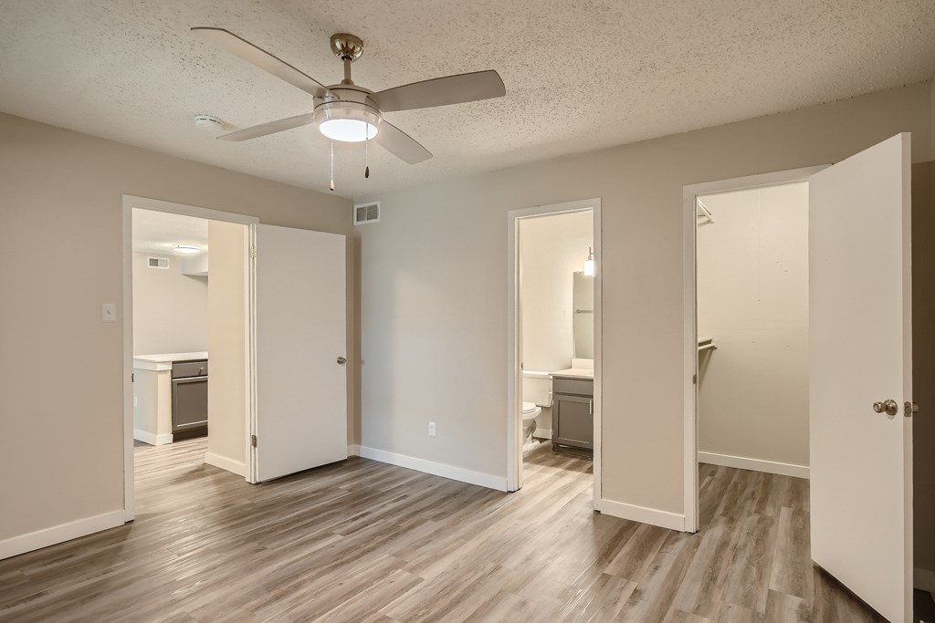 A room with a ceiling fan and wooden floors.