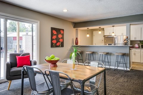 A dining room with a table set for two and a view of the backyard.