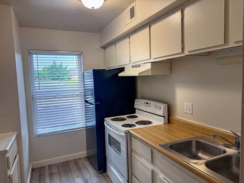 A kitchen with a black refrigerator and white appliances.