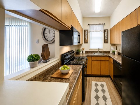 A kitchen with wooden cabinets and a black refrigerator.