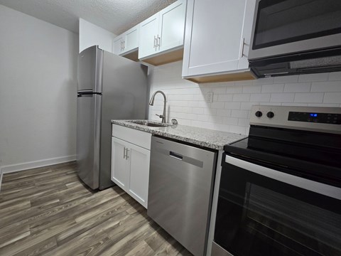 A kitchen with a stainless steel refrigerator, dishwasher, and oven.