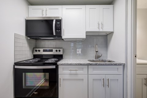 A kitchen with a black stove top oven and white cabinets.