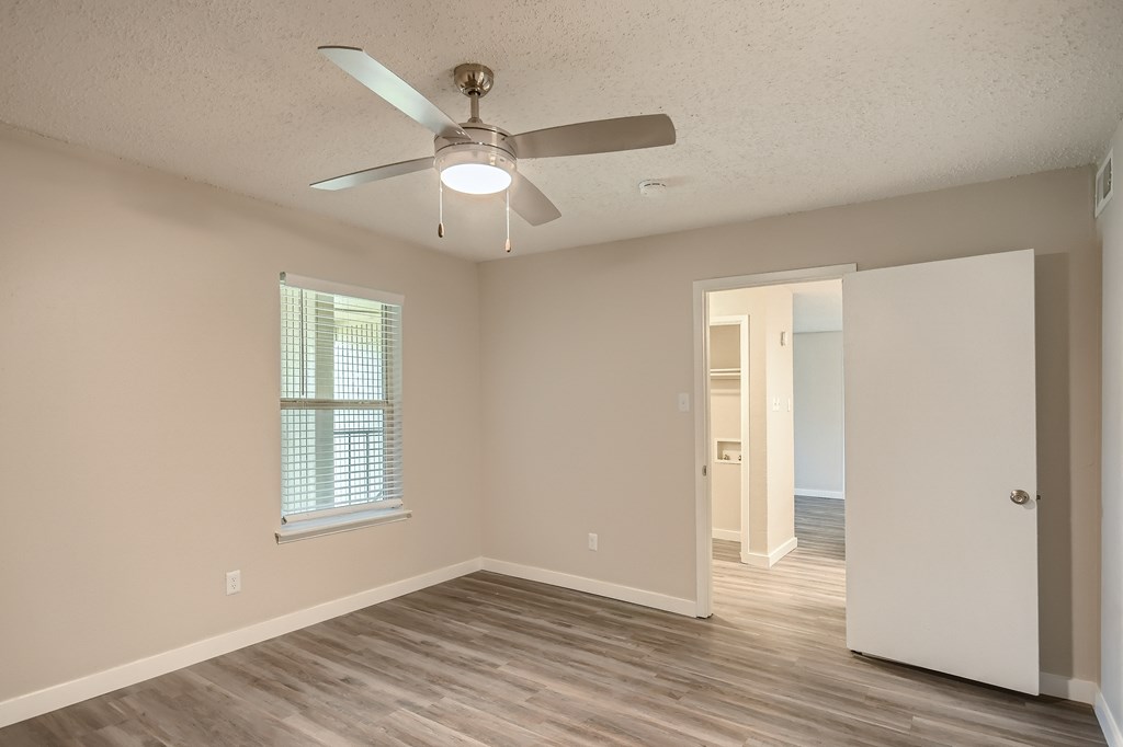 A room with a ceiling fan and a window with blinds.
