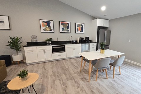A kitchen with a table and chairs in the foreground and a refrigerator in the background.