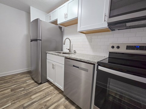 A kitchen with a refrigerator, dishwasher, and oven.