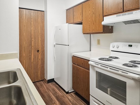 A white refrigerator and stove in a kitchen with wooden cabinets.