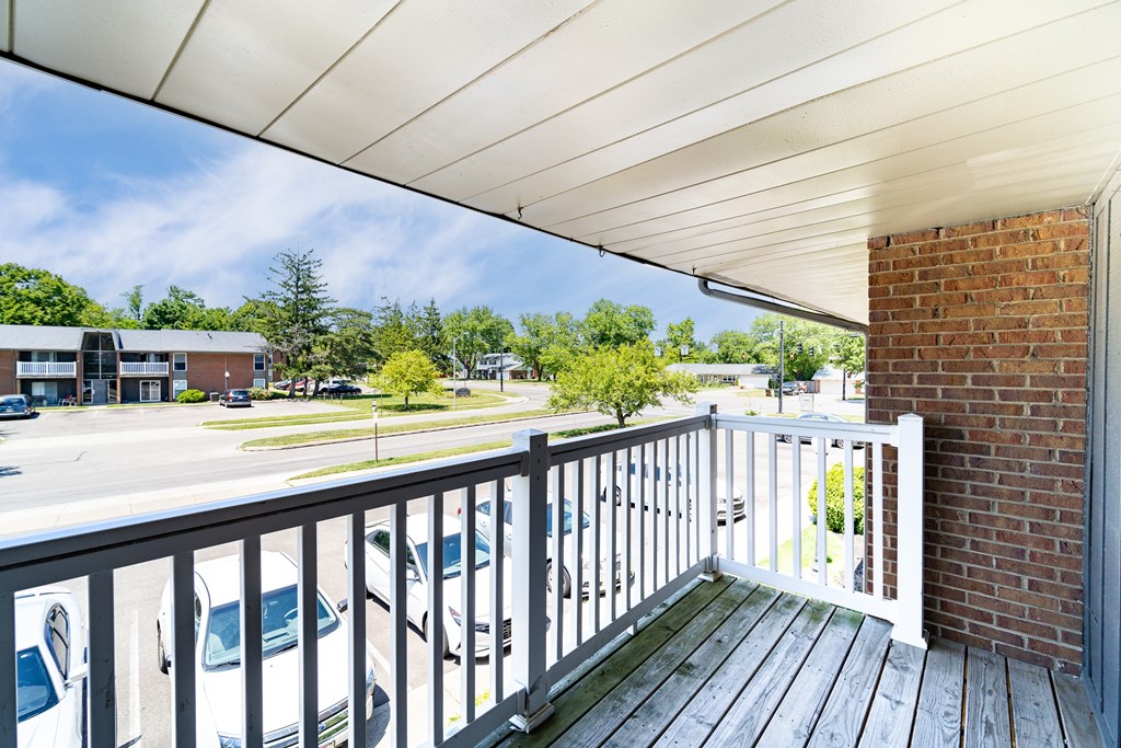 A balcony with a white railing and a brick pillar.