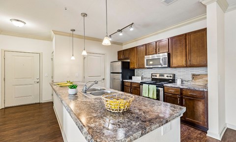 A kitchen with a granite countertop and wooden cabinets.