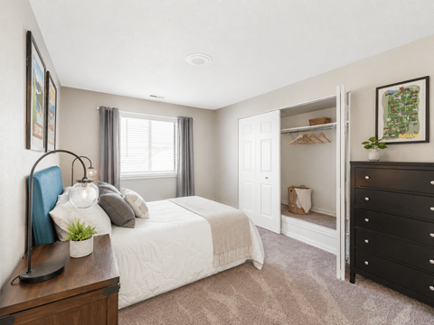 A bedroom with a white bed and a black dresser.