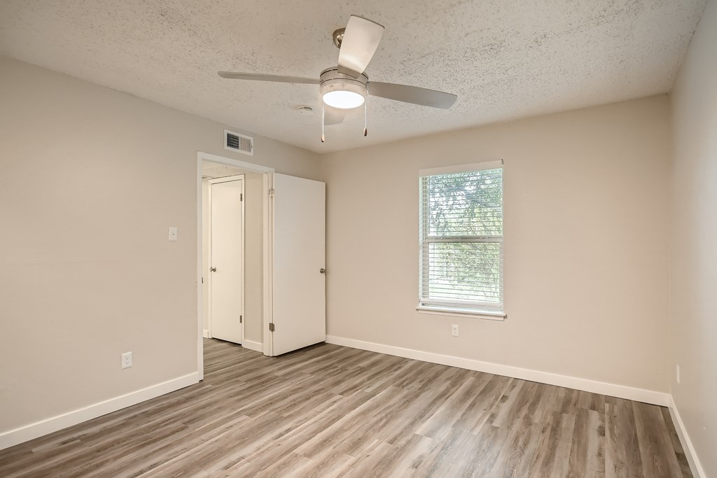 A room with a ceiling fan and a window with blinds.