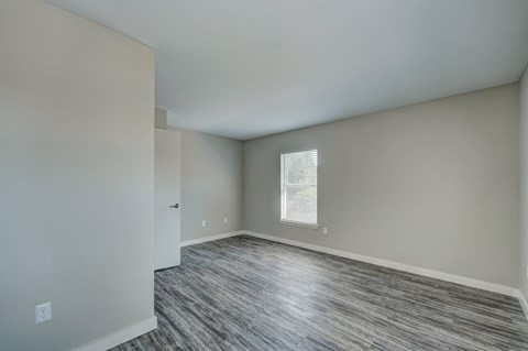 A room with a window and a wooden floor.