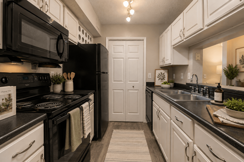 A kitchen with black appliances and white cabinets.