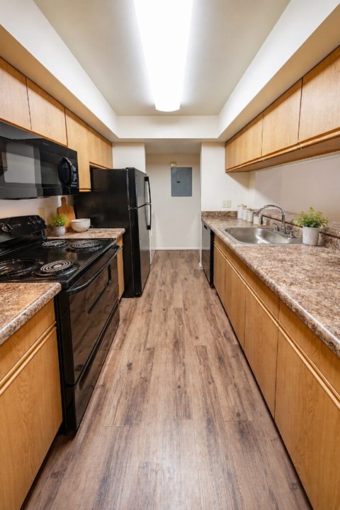 A kitchen with wooden cabinets and a black refrigerator.
