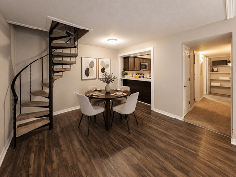 A dining room with a spiral staircase and a table set for two.
