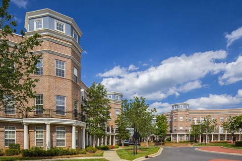 a large brick building with trees and a street in front of it
