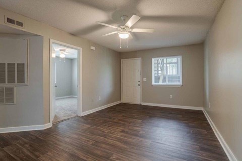 Empty room with wooden floors and a ceiling fan.
