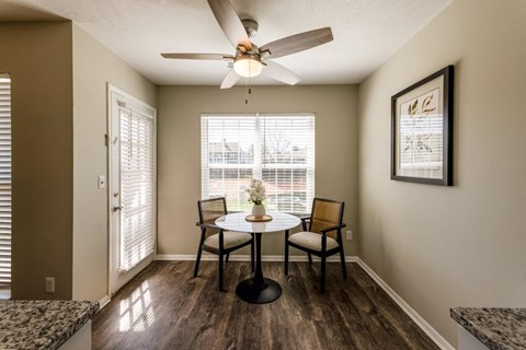 A dining room with a table and chairs and a ceiling fan.