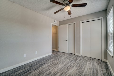 A room with a ceiling fan and wood flooring.